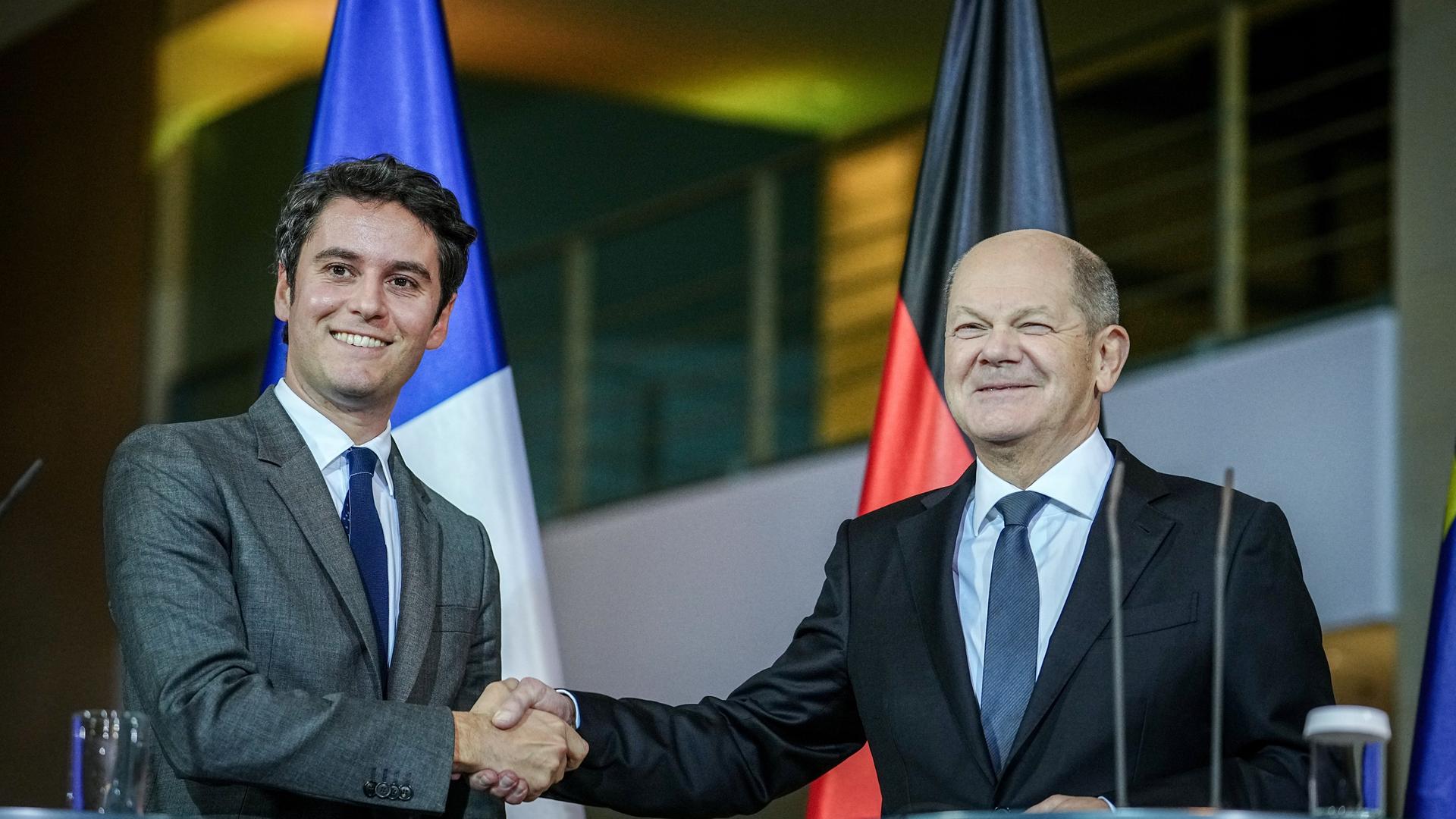 Bundeskanzler Olaf Scholz (SPD, r) und der französische Premierminister Gabriel Attal geben sich Bundeskanzleramt die Hand. Im Hintergrund ist die franzöische und die deutsche Fahne zu sehen. 