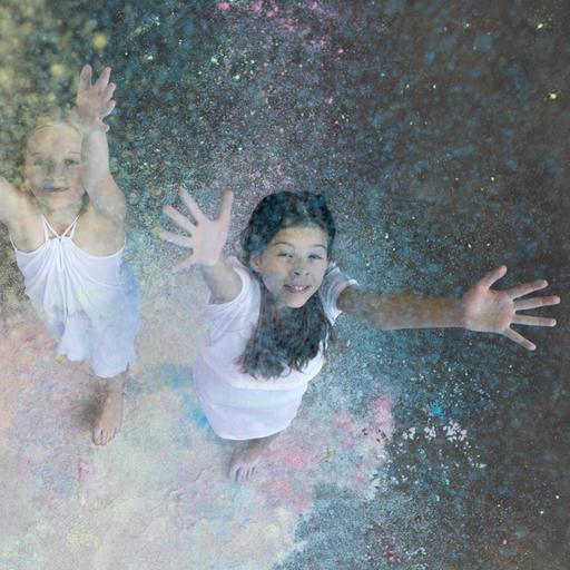 Zwei Mädchen werfen Farbpulver in die Luft. 