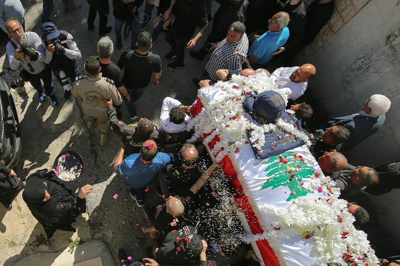 Eine Frau wirft Reis und Rosenblätter auf den reich geschmückten Sarg der libanesischen Journalistin Amal Khalil. Weitrere Menschen stehen daneben.
