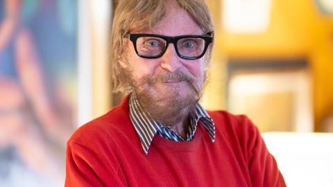 Der Kunstsammler Frank Brabant steht in seiner Wohnung in Wiesbaden. Er trägt eine schwarze Brille, einen roten Pullover und schaut freundlich in die Kamera. Der Kunstsammler Frank Brabant steht in seiner Wohnung in Wiesbaden. Er trägt eine schwarze Brille, einen roten Pullover und schaut freundlich in die Kamera.
