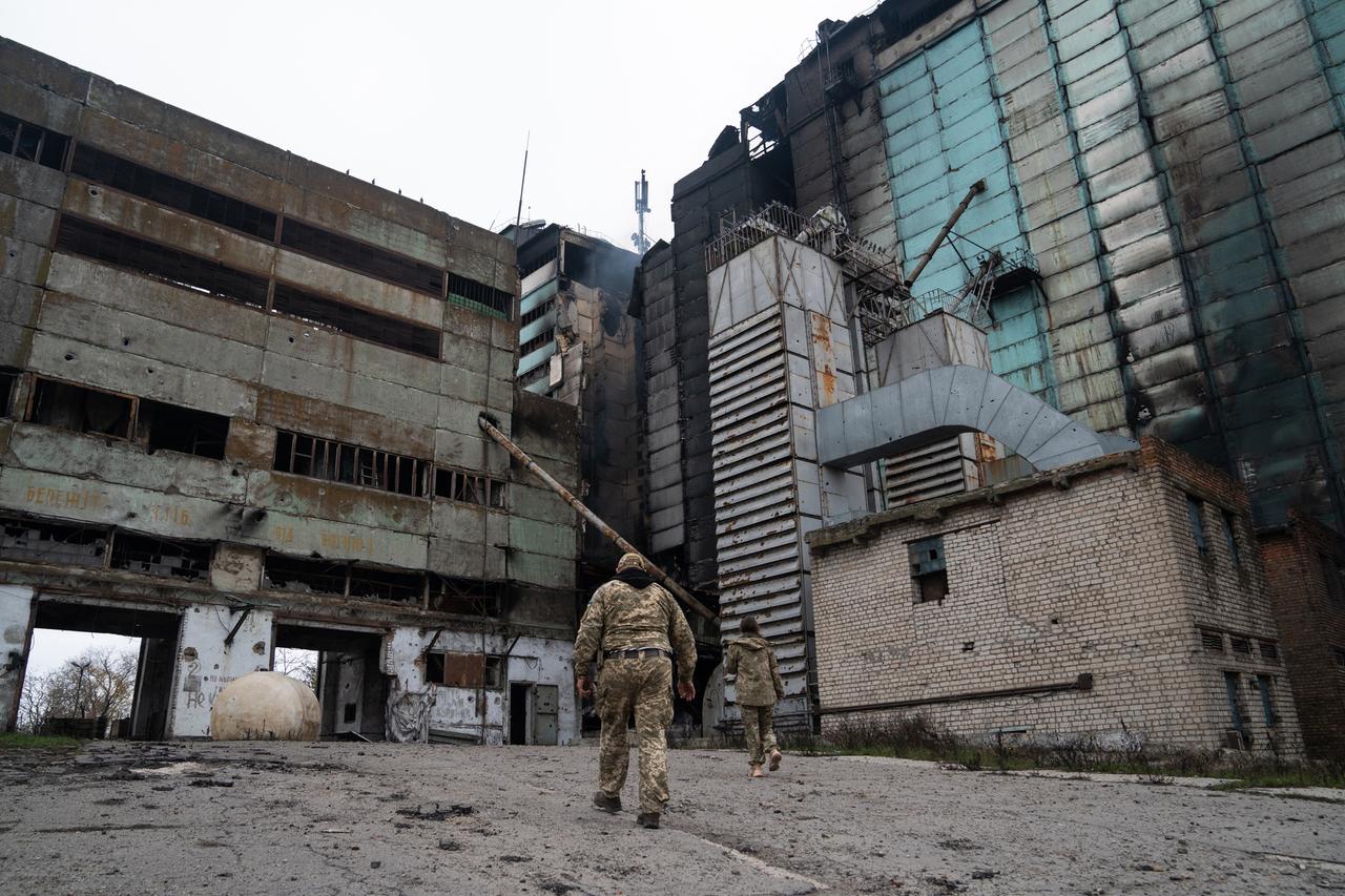 Ukrainische Soldaten laufen auf ein ausgebranntes Industriegebäude im Gebiet Cherson zu. In der Mitte raucht es noch.