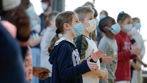 Kinder stehen in einer Turnhalle und klatschen in die Hände. Tourstart des Projekts "Wir wollen mobbingfrei!" 2021 in Düsseldorf.