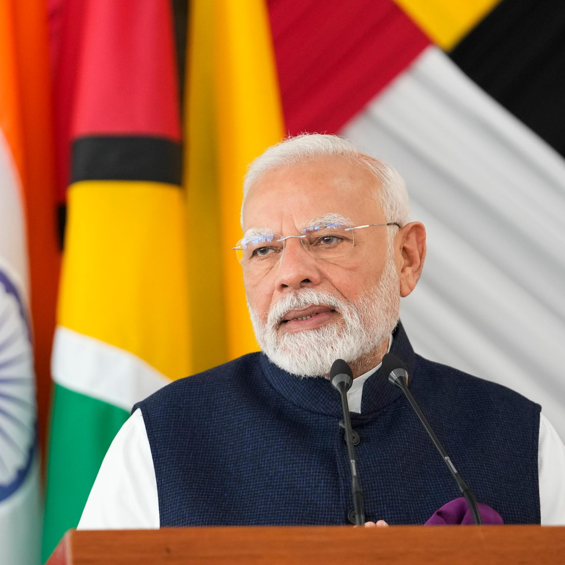 Indiens Premierminister Narendra Modi während eines Besuchs in Guyana. Im Hintergrund sind die Nationalflaggen.