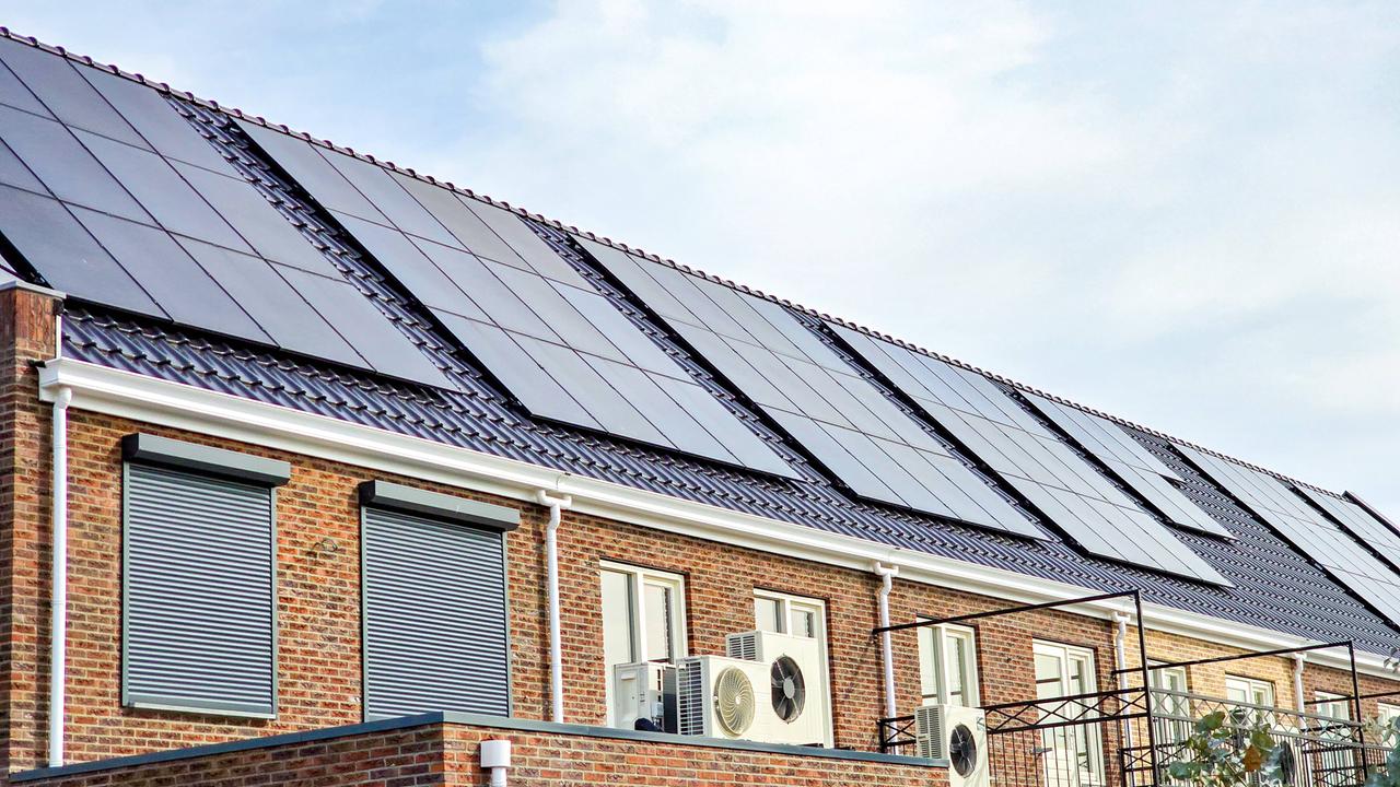 An der Fassade mehrerer Häuser sind Wärmepumpen und Solarmodule installiert.