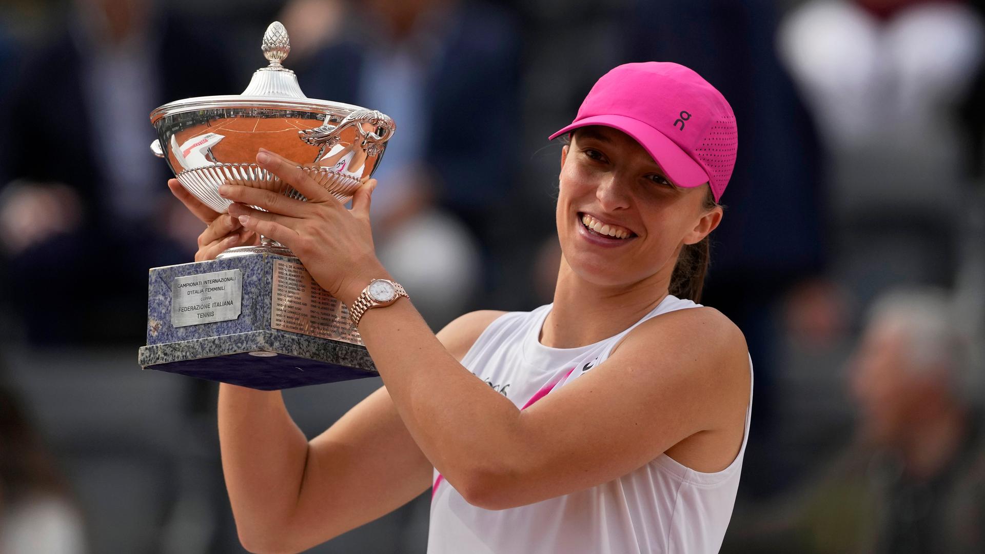 Tennisspielerin Iga Swiatek aus Polen hält die Trophäe in beiden Händen und lächelt. Tennisspielerin Iga Swiatek aus Polen hält die Trophäe in beiden Händen und lächelt.
