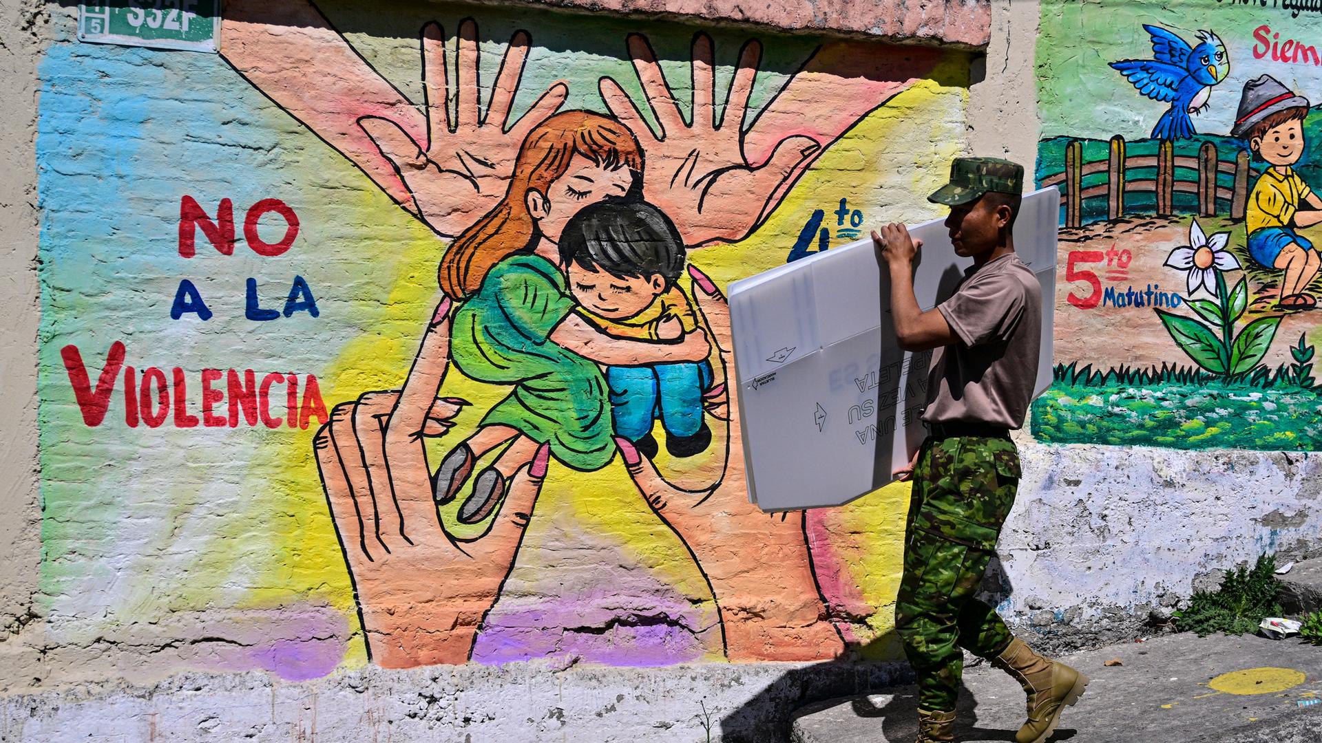 Ein Militärangehöriger in Ecuador transportiert in der Hauptstadt Quito Material für die Präsidentschaftswahl. Auf einem Graffito im Hintergrund steht "Nein zur Gewalt".