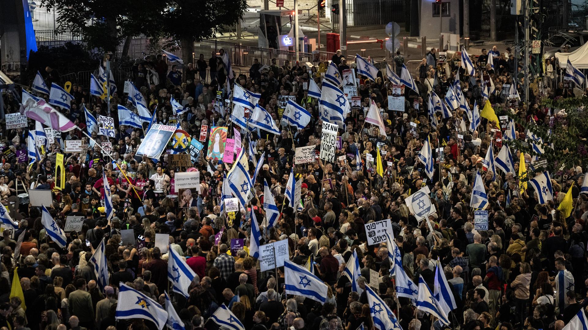 Ein Platz ist voller Menschen, die Plakate halten und israelische Flaggen schwenken.