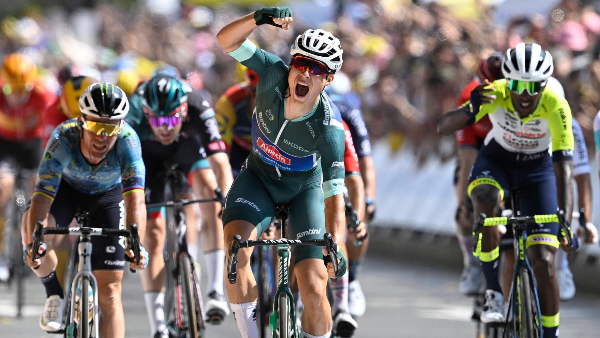 Der Belgier Jasper Philipsen freut sich über seinen Sieg bei der siebten Etappe der Tour de France. Er fährt ins Ziel und streckt die rechte Hand nach oben. Hinter ihm sind weitere Radrennfahrer zu sehen. Der Belgier Jasper Philipsen freut sich über seinen Sieg bei der siebten Etappe der Tour de France. Er fährt ins Ziel und streckt die rechte Hand nach oben. Hinter ihm sind weitere Radrennfahrer zu sehen.