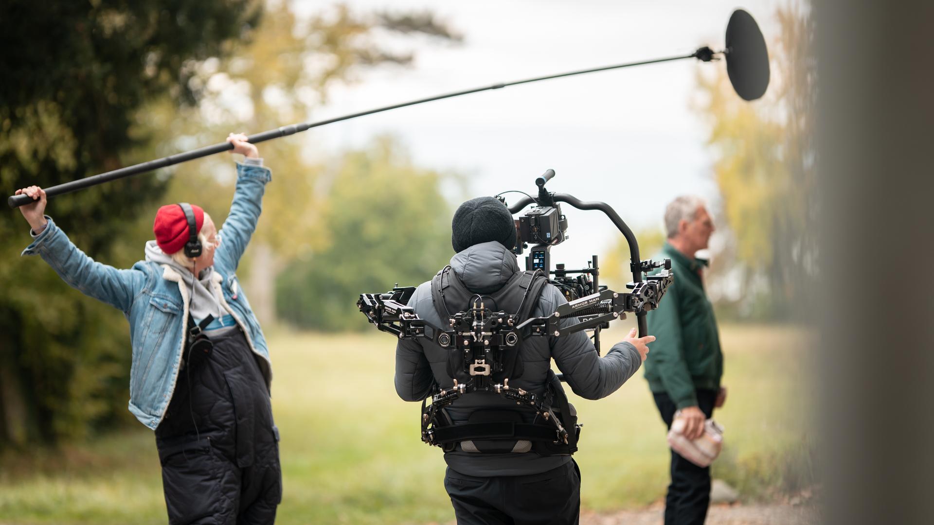 Eine Tonfrau mit einer Mikroangel über ihrem Kopf und ein Kameramann von hinten beim Filmdreh. Eine Tonfrau mit einer Mikroangel über ihrem Kopf und ein Kameramann von hinten beim Filmdreh.