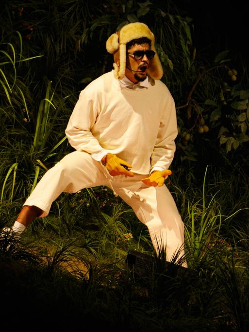 Bad Bunny steht mit einer Wintermütze auf einer Bühne und trägt Sonnenbrille, während er in ein Mikro singt