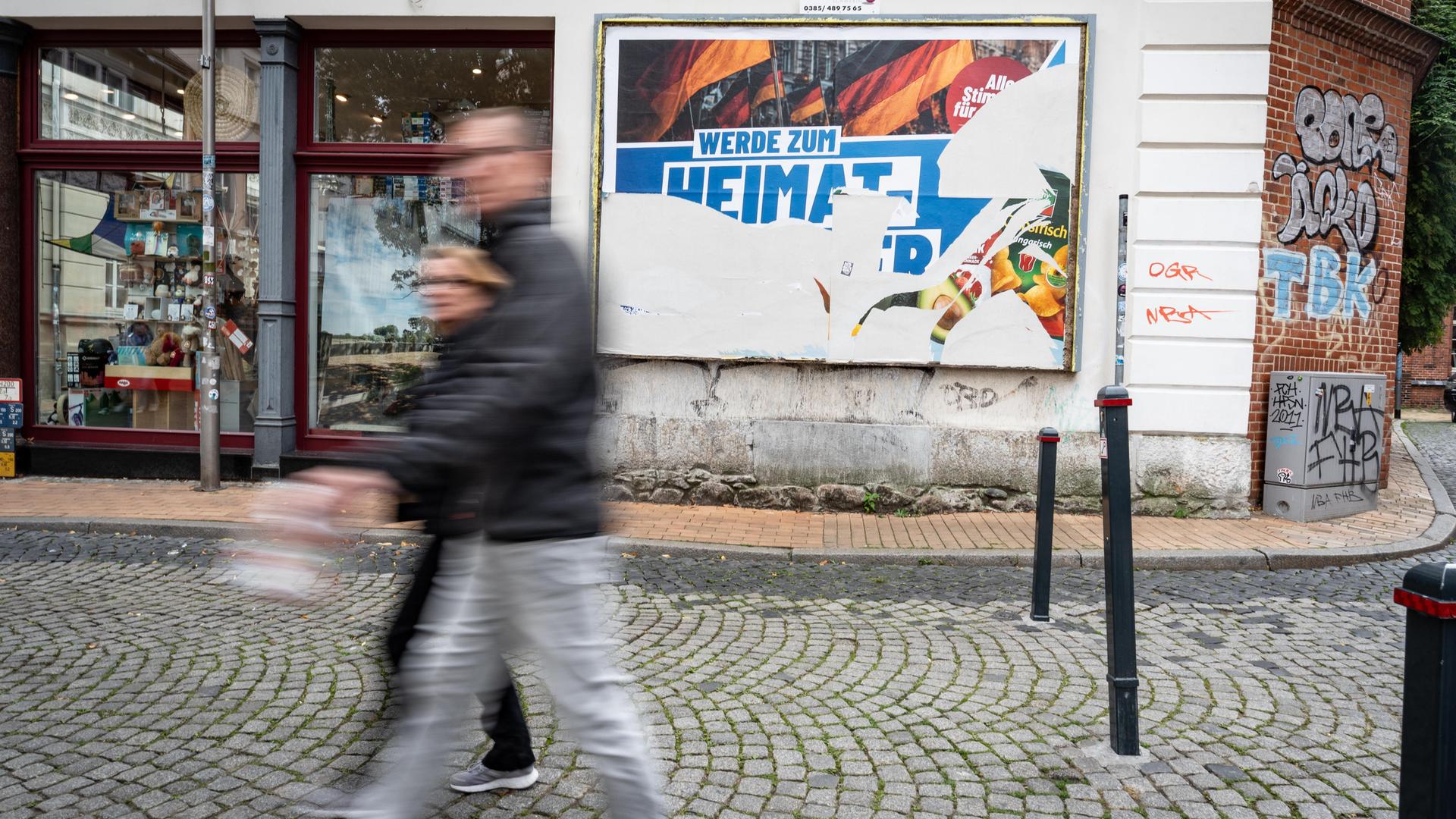 Eine Szene in der Fußgängerzone von Schwerin: Ein beschädigtes Wahlplakat der AfD am Tag vor der Landtagswahl 2026 in Mecklenburg-Vorpommern. Darauf steht der Slogan "Werde zum Heimatretter".