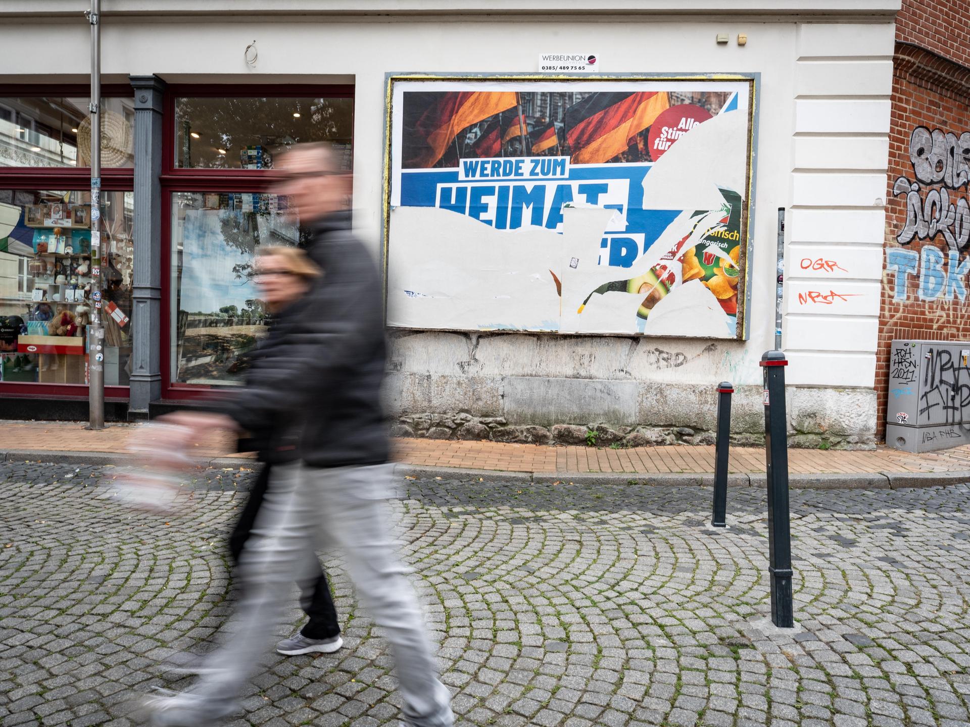 Eine Szene in der Fußgängerzone von Schwerin: Ein beschädigtes Wahlplakat der AfD am Tag vor der Landtagswahl 2026 in Mecklenburg-Vorpommern. Darauf steht der Slogan "Werde zum Heimatretter". Eine Szene in der Fußgängerzone von Schwerin: Ein beschädigtes Wahlplakat der AfD am Tag vor der Landtagswahl 2026 in Mecklenburg-Vorpommern. Darauf steht der Slogan "Werde zum Heimatretter".