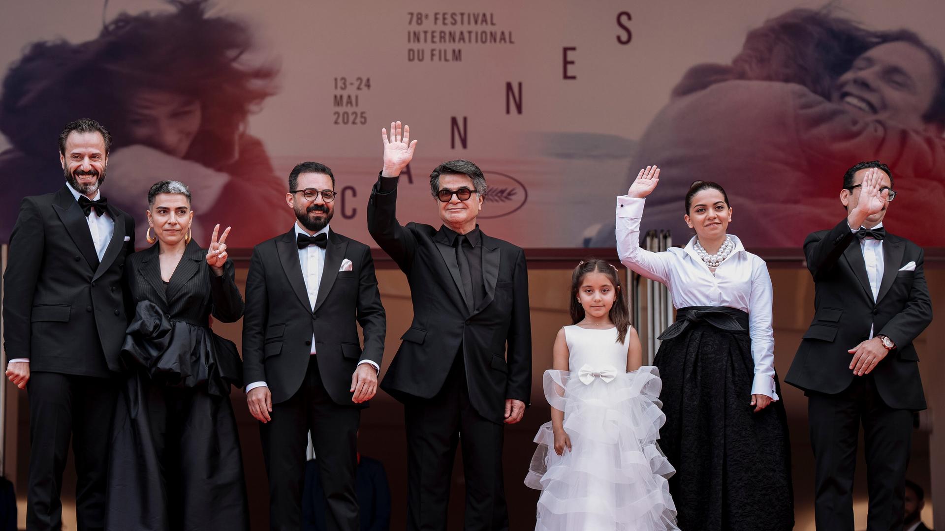 Regisseur Jafar Panahi inmitten von Teilen seiner Filmcrew auf dem roten Teppich beim Filmfestival in Cannes. Dahinter ein Großplakat seines Films "Ein einfacher Unfall" Regisseur Jafar Panahi inmitten von Teilen seiner Filmcrew auf dem roten Teppich beim Filmfestival in Cannes. Dahinter ein Großplakat seines Films "Ein einfacher Unfall"