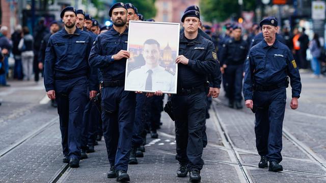 Polizisten tragen bei einem Trauermarsch für den bei einer Messerattacke in Mannheim tödlich verletzten Polizisten Rouven Laur dessen Bild. 