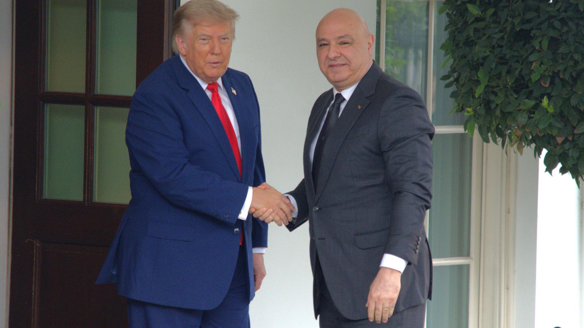 US-Präsident Donald Trump schüttelt Libanons Präsident Joseph Aoun im Weißen haus die Hand. Im Hintergrund der weiß gehaltene Eingangsbereich. 