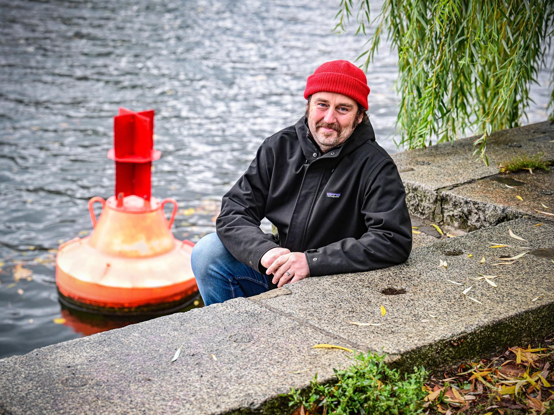 Ein Mann mit einer Mütze auf dem Kopf sitzt an einem Kanal in Berlin