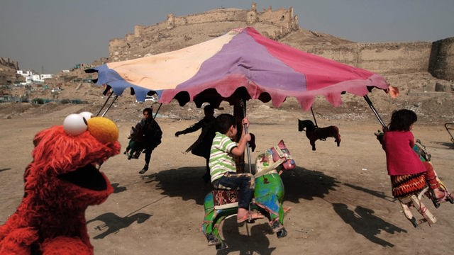 Elmo vor einem Karussell, mit dem afghanische Kinder in der Nähe von Kabul fahren