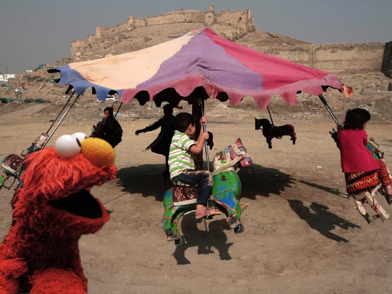 Elmo vor einem Karussell, mit dem afghanische Kinder in der Nähe von Kabul fahren