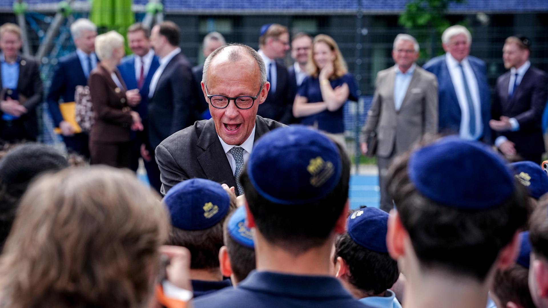 Bundeskanzler Friedrich Merz (CDU) begrüßt Schüler in der jüdischen Chabad Gemeinde Berlin auf dem Pears Campus, die von hinten zu sehen sind.