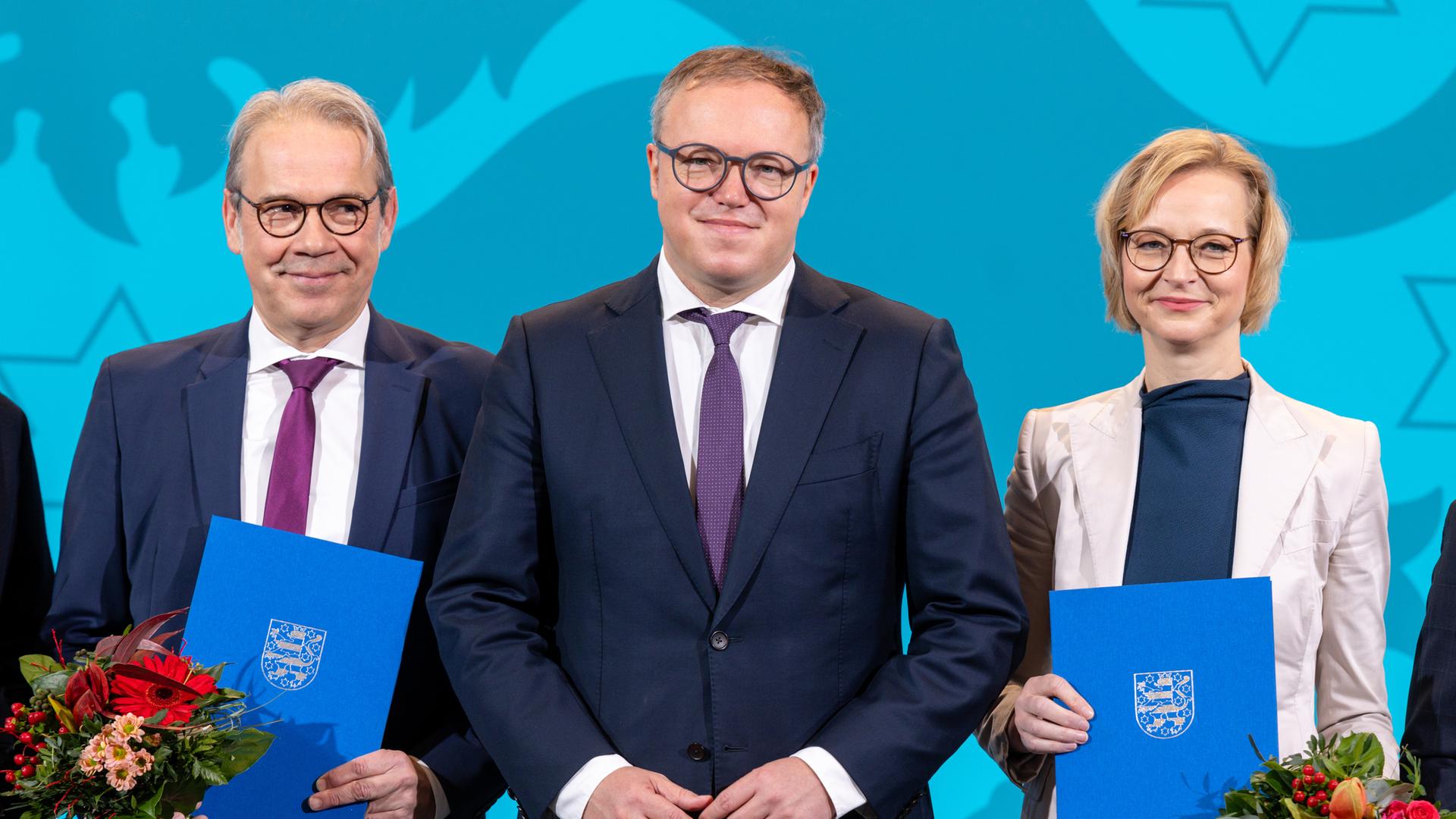 Georg Maier (SPD), Mario Voigt (CDU), Thüringer Ministerpräsident und Katja Wolf (BSW) halten Urkunden und Blumen bei der Ernennung der Thüringer Ministerinnen und Minister im Thüringer Landtag.