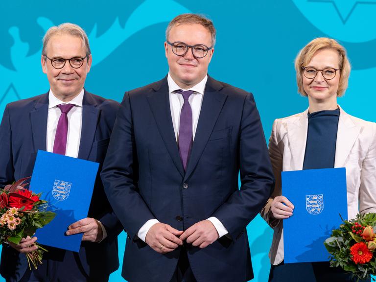 Georg Maier (SPD), Mario Voigt (CDU), Thüringer Ministerpräsident und Katja Wolf (BSW) halten Urkunden und Blumen bei der Ernennung der Thüringer Ministerinnen und Minister im Thüringer Landtag.