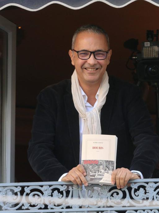 Der algerisch-französische Schriftsteller Kamel Daoud präsentiert sich und sein Buch "Houris" an einem offenen Fenster, nachdem er den französischen Literaturpreis, den Prix Goncourt 2024, erhalten hat.