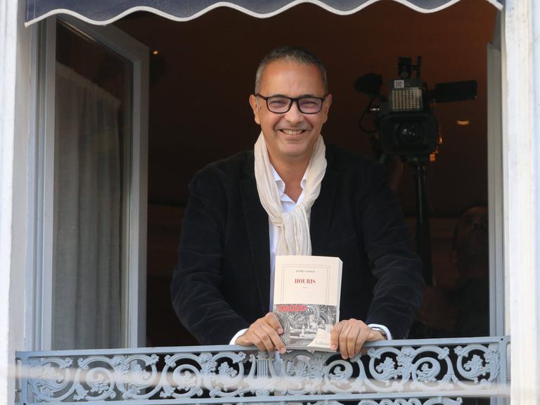 Der algerisch-französische Schriftsteller Kamel Daoud präsentiert sich und sein Buch "Houris" an einem offenen Fenster, nachdem er den französischen Literaturpreis, den Prix Goncourt 2024, erhalten hat.