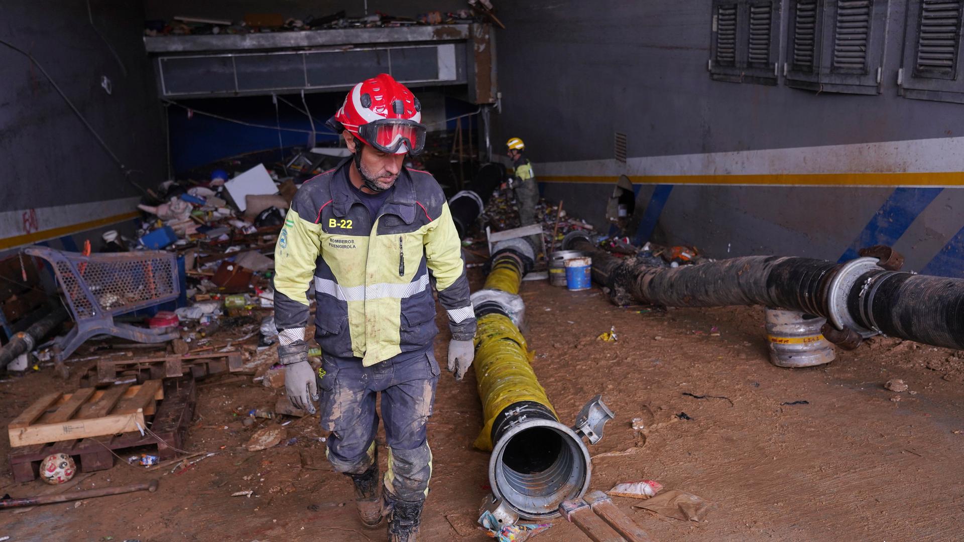 Ein Feuerwehrmann bewegt sich über die verschlammte und mit Unrat versperrte Auffahrt einer Tiefgarage. Große Schläuche sind ausgelegt. Ein Feuerwehrmann bewegt sich über die verschlammte und mit Unrat versperrte Auffahrt einer Tiefgarage. Große Schläuche sind ausgelegt.