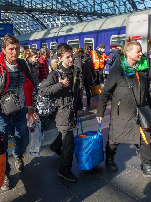 Ukrainische Flüchtlinge kommen am Berliner Hauptbahnhof an. Eine Familie geht mit Gepäck den Bahnsteig entlang.