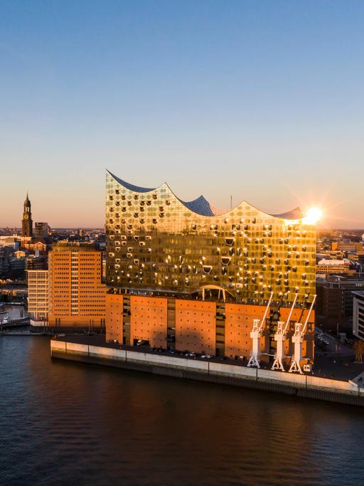 Die Hamburger Elbphilharmonie vom Wasser aus betrachtet im Sonnenuntergang.