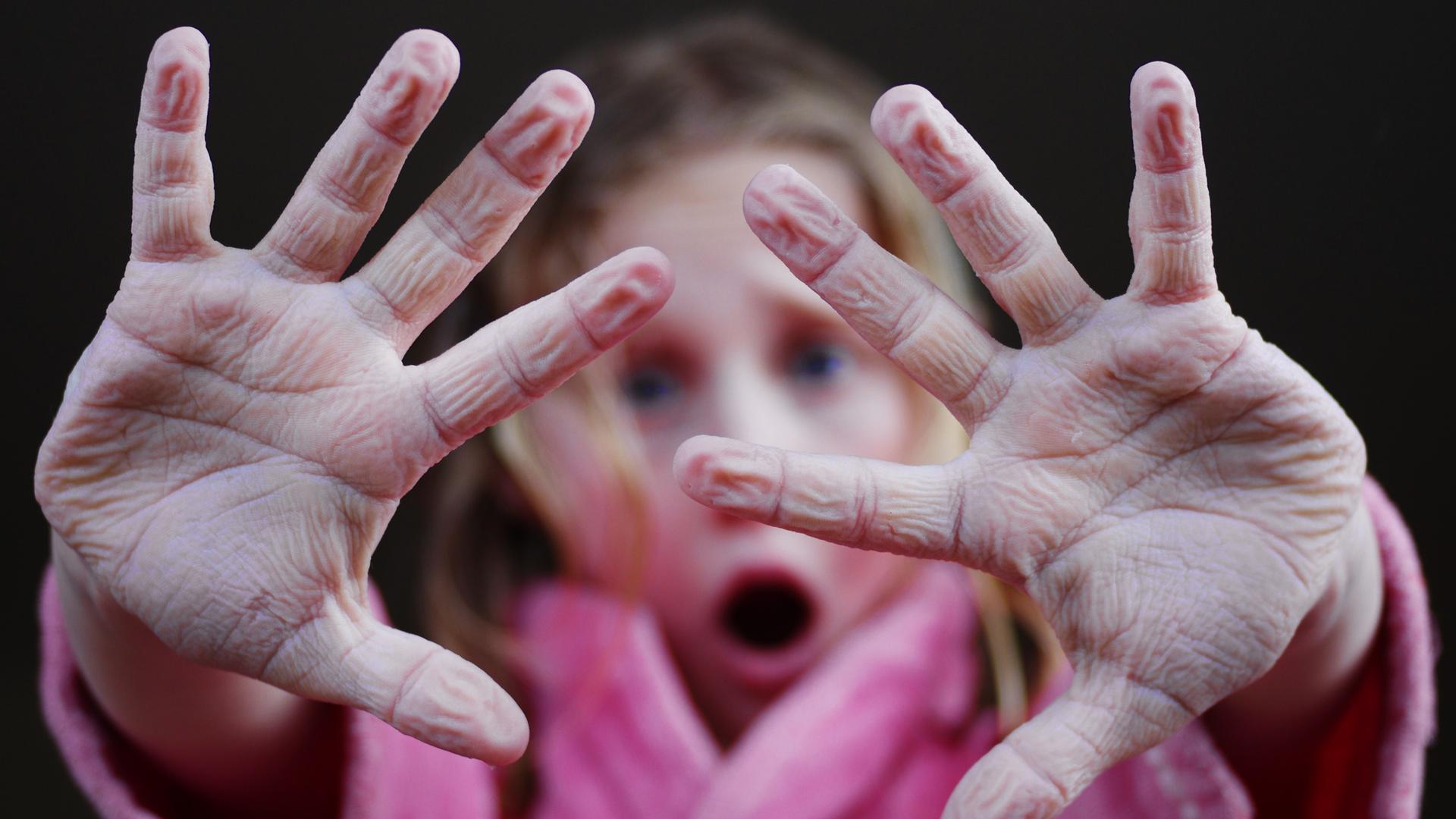 Mädchen hält schrumpelige Finger hoch