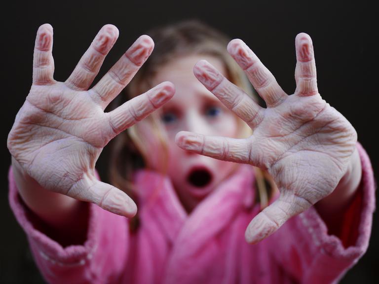 Mädchen hält schrumpelige Finger hoch