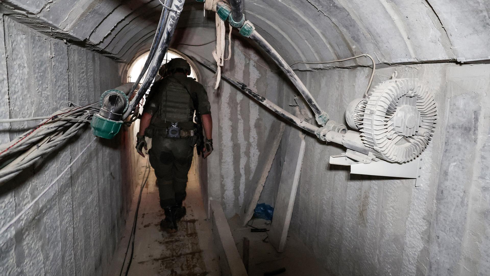 Der Soldat geht durch den engen Tunnel. Versorgungskabel und Schläuche verlaufen in Richtung Tunneldecke. 