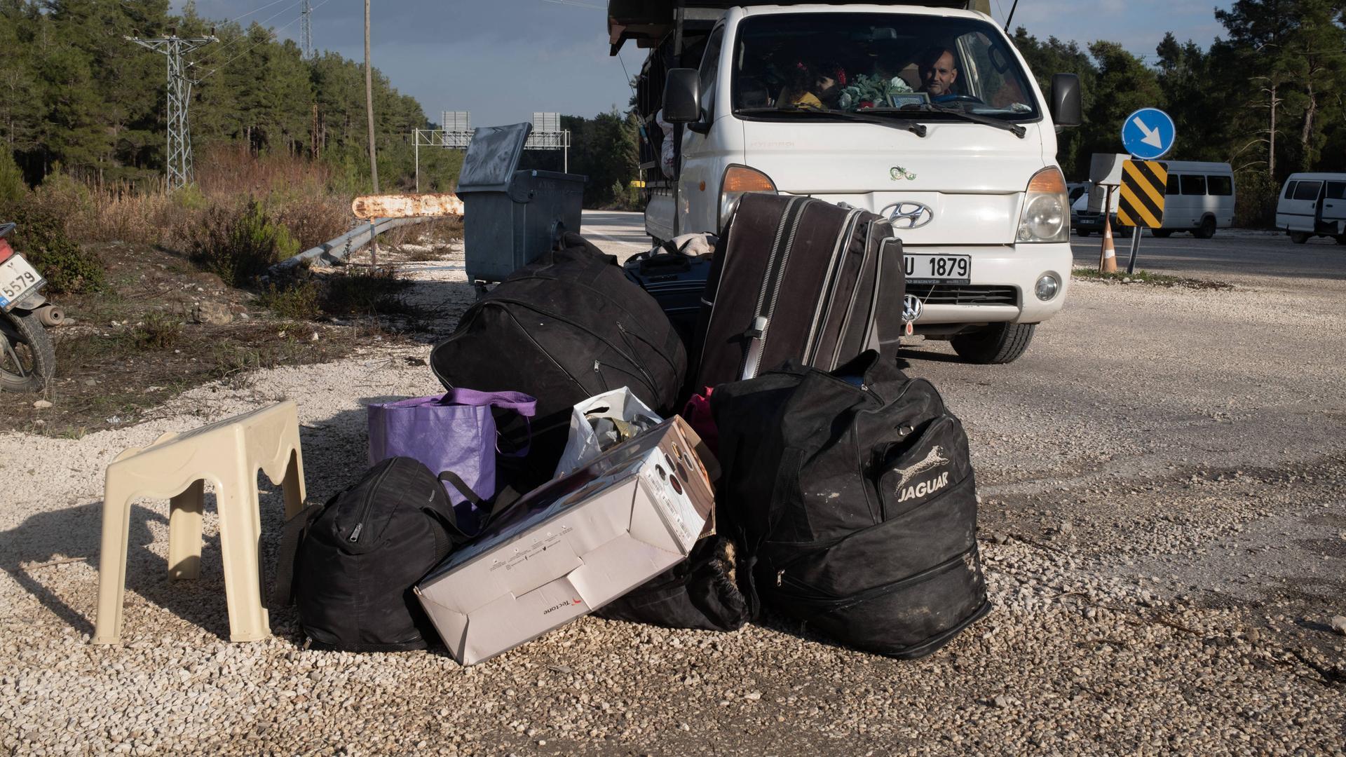 Syrische Flüchtlinge kehren aus der Türkei in ihre Heimat zurück. Ein Mann sitzt in einem Kleinstransporter und vor ihm liegt Gepäck auf der Straße