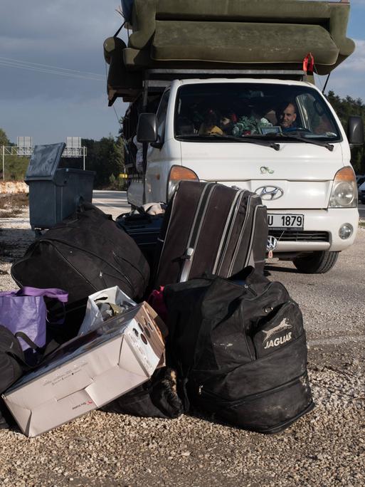 Syrische Flüchtlinge kehren aus der Türkei in ihre Heimat zurück. Ein Mann sitzt in einem Kleinstransporter und vor ihm liegt Gepäck auf der Straße