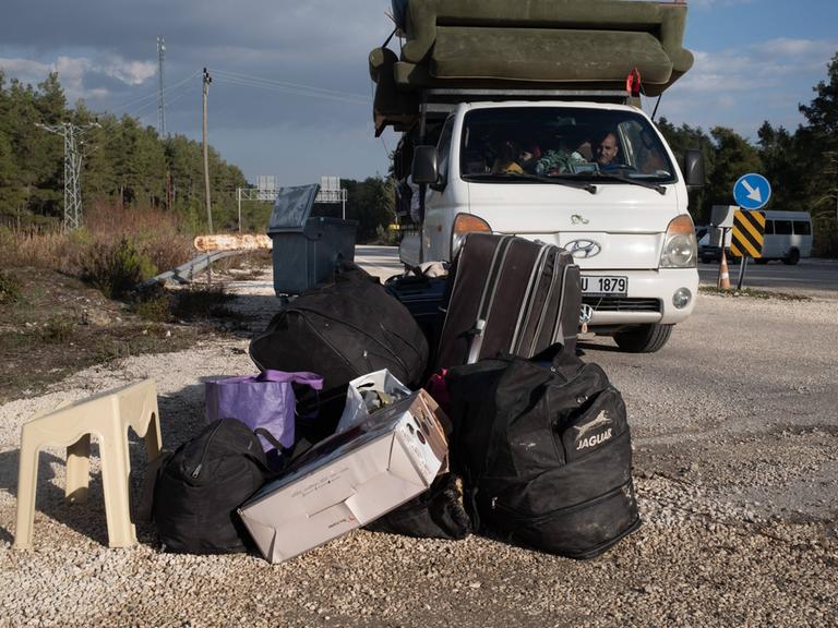 Syrische Flüchtlinge kehren aus der Türkei in ihre Heimat zurück. Ein Mann sitzt in einem Kleinstransporter und vor ihm liegt Gepäck auf der Straße