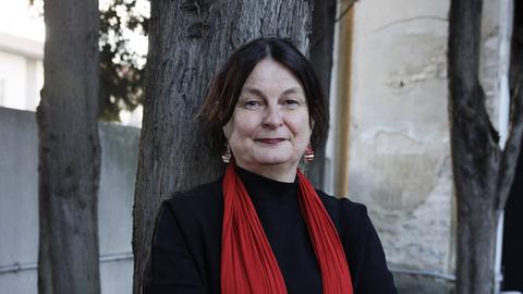 Porträtfoto einen Frau mit rotem Schal, die mit verschränkten Armen vor einem Baumstamm steht. Porträtfoto einen Frau mit rotem Schal, die mit verschränkten Armen vor einem Baumstamm steht.