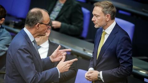Christian Lindner (FDP, l), Bundesminister der Finanzen, und Friedrich Merz (CDU), CDU-Bundesvorsitzender und Unionsfraktionsvorsitzender, nehmen im Plenum an der Sitzung des Bundestags teil. Sie stehen sich gegenüber und unterhalten sich.