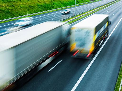 Im Vordergrund fahren auf einer sechsspurigen Autobahn in Polen zwei LKW. Im Hintergrund sind noch zwei Autos erkennbar.