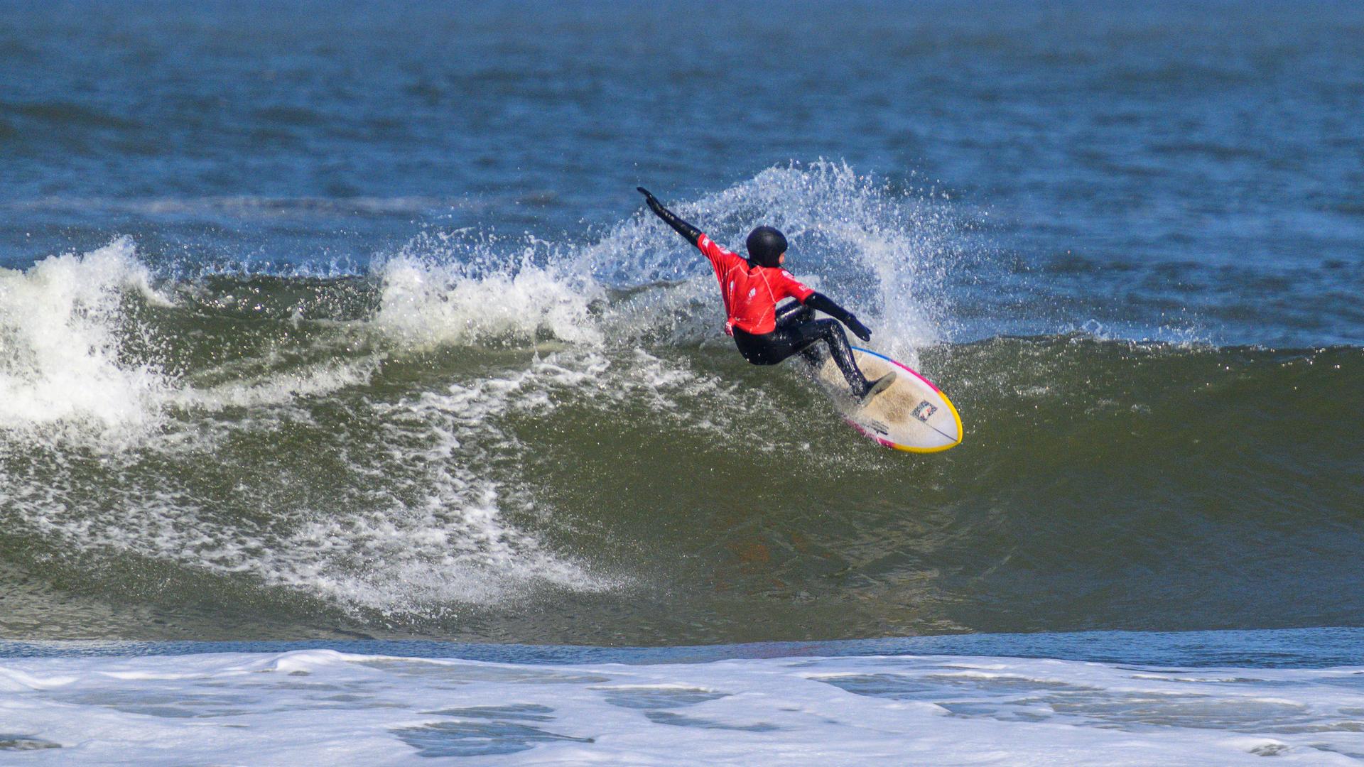 Auf dem Bild ist ein Surfer zu sehen, der über eine Welle reitet. 