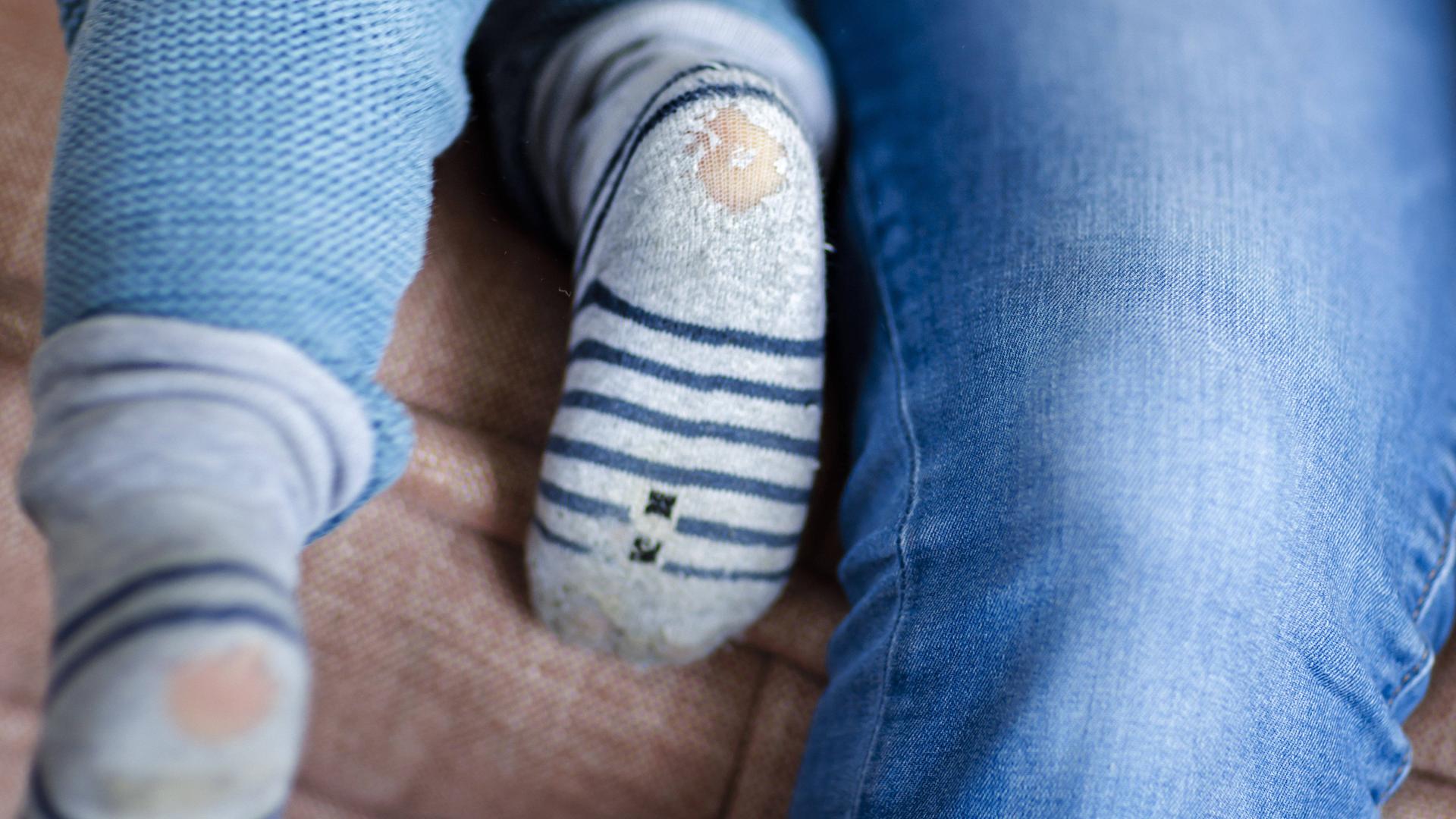 Symbolbild zum Thema Kinderarmut: Ein Baby mit kaputten Socken