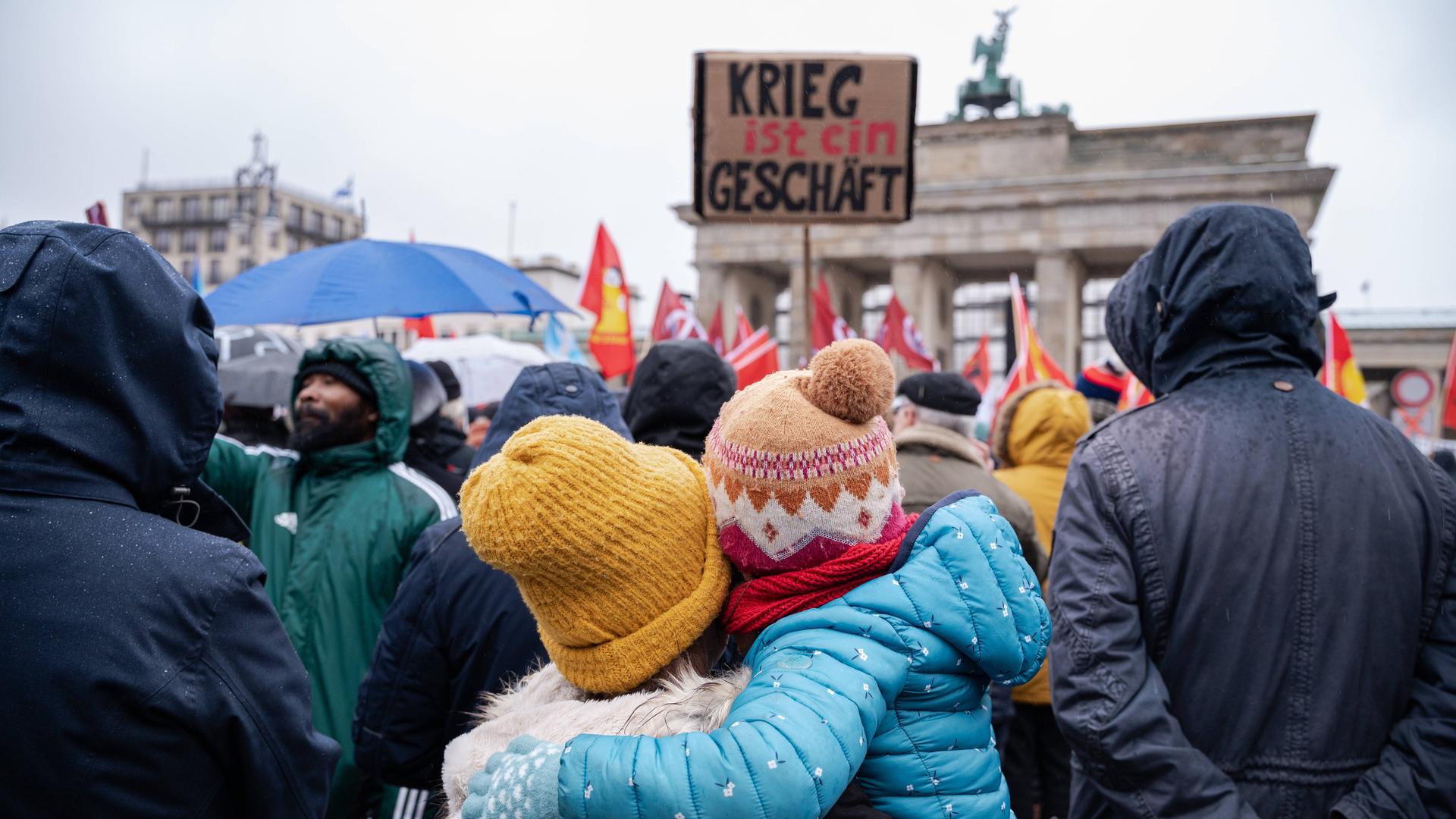 Einige tausend Menschen demonstrieren am Brandenburger Tor im Berliner Bezirk Mitte für den Frieden unter dem Titel Nein zu Kriegen - Rüstungswahnsinn stoppen. Auf einem Schild steht "Krieg ist ein Geschäft".