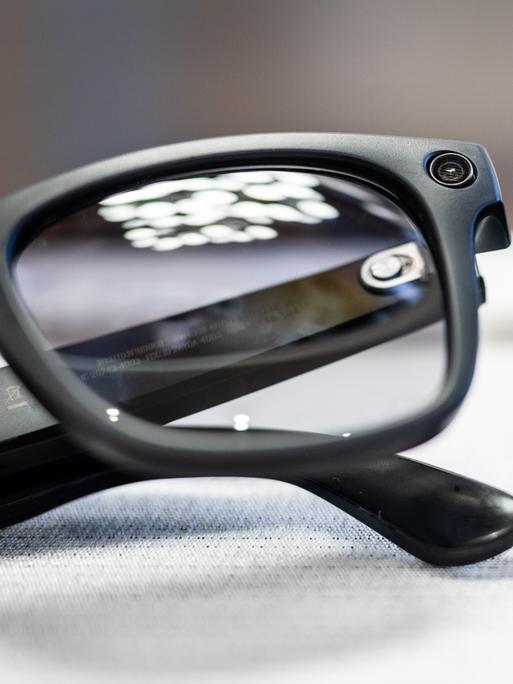 Smarte Datenbrillen der Firmen Oakley Meta und Ray-Ban Meta liegen in einem Brillenfachgeschäft auf einem Tisch. 