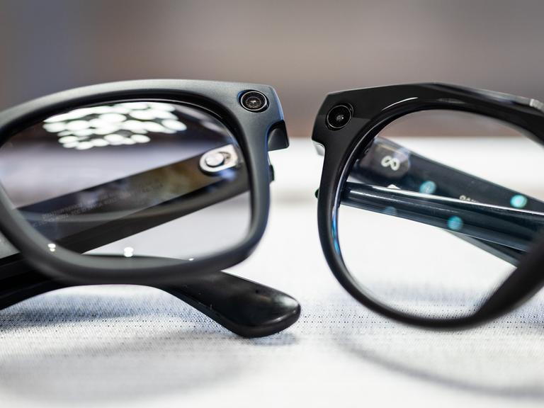 Smarte Datenbrillen der Firmen Oakley Meta und Ray-Ban Meta liegen in einem Brillenfachgeschäft auf einem Tisch. 