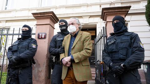 Bei einer Razzia gegen sogenannte "Reichsbürger" führen vermummte Polizisten nach der Durchsuchung eines Hauses Heinrich Reuß zu einem Polizeifahrzeug. 