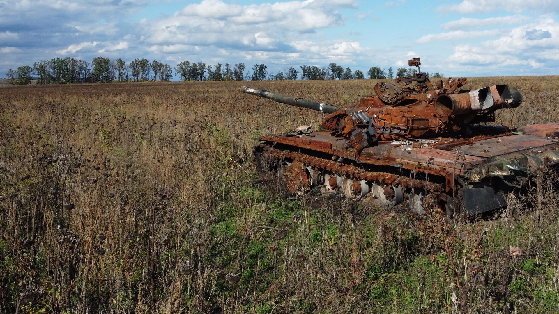 Ein zerstörter und verrosteter russischer Panzer auf einem ukrainischen Acker.