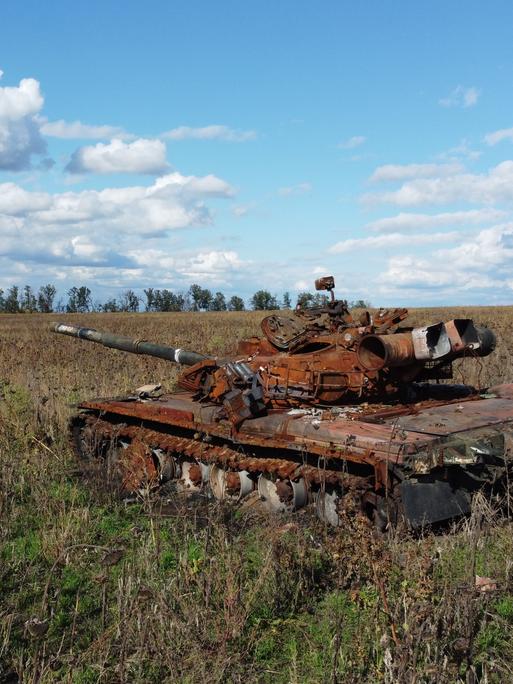 Ein zerstörter und verrosteter russischer Panzer auf einem ukrainischen Acker.