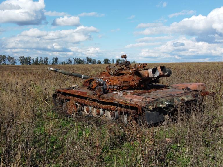 Ein zerstörter und verrosteter russischer Panzer auf einem ukrainischen Acker.