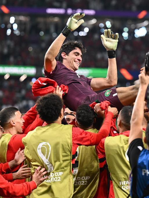 Marokkos Torwart Bono und seine Mitspieler jubeln nach dem Sieg im Elfmeterschiessen gegen Spanien bei der Fußball-WM 2022 in Katar. Die Spieler werfen ihren Torwart vor Freude in die Luft und lassen ihn hochleben