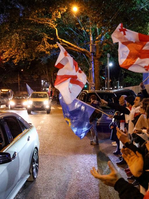 Menschen schwenken georgische Flaggen und feiern den Sieg der Partei „Georgischer Traum - Demokratisches Georgien“ bei den Parlamentswahlen in Georgien 2024. 